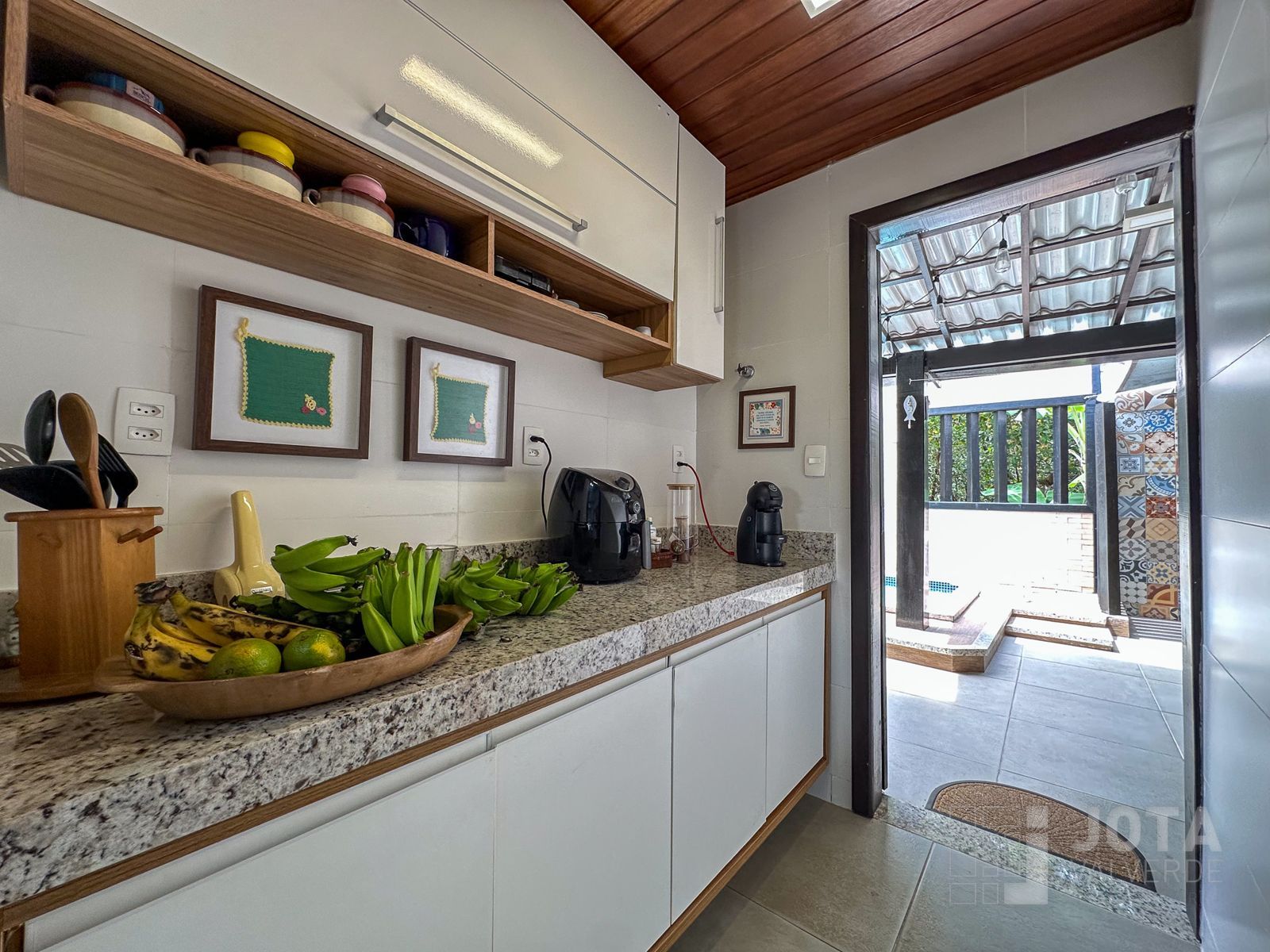 Cozinha planejada com bancada em granito e saída direta para a área gourmet