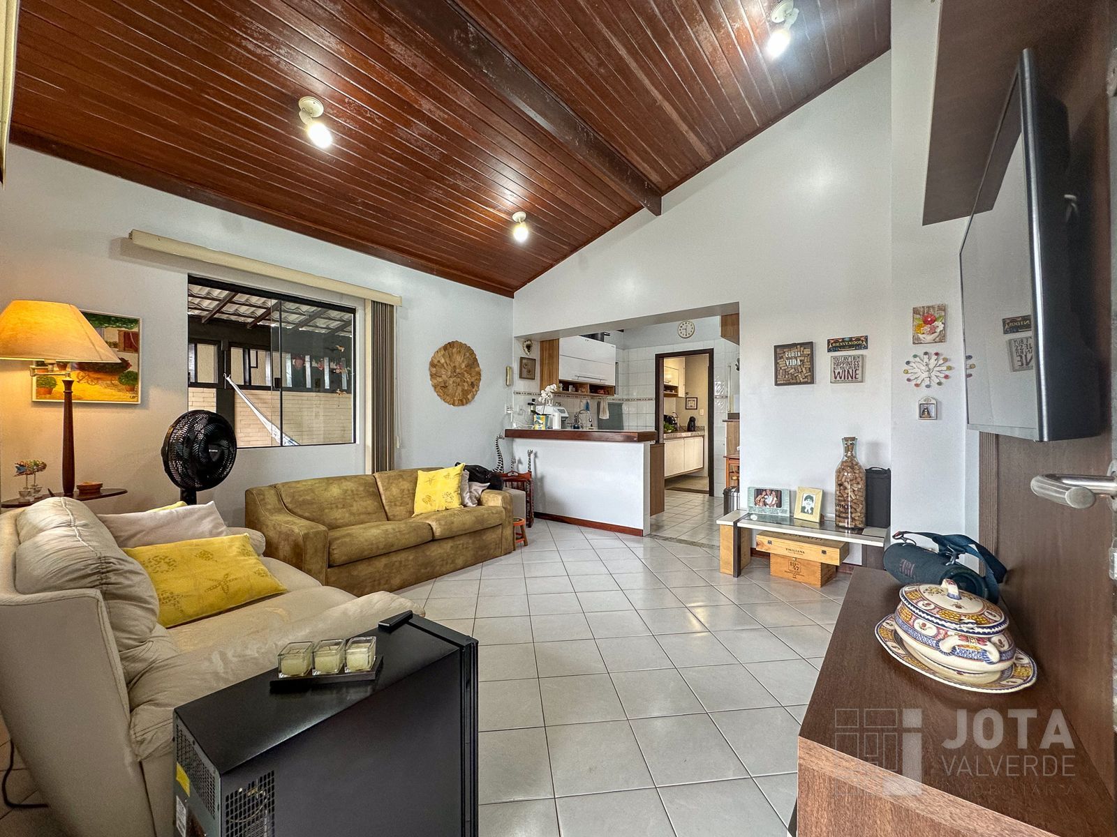 Sala de estar integrada, com pé-direito alto e forro de madeira